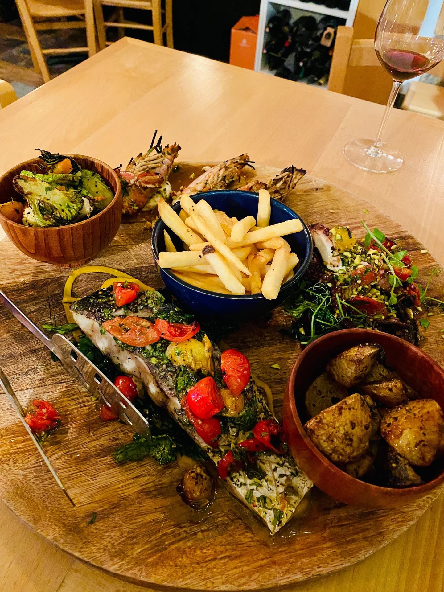 Platter with grilled fish, king prawns, French fries, roasted potatoes and fresh salad